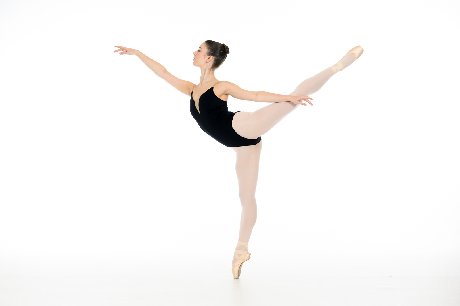 Ballerina in black leotard performing an arabesque en pointe in a white studio, Spokane ballet photography